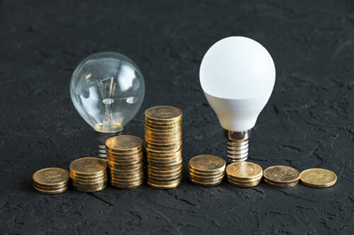 Energy saving. Energy saving light bulb and old bulb.Money coins on a dark background. Energy saving. Stack of coins.Environmental protection